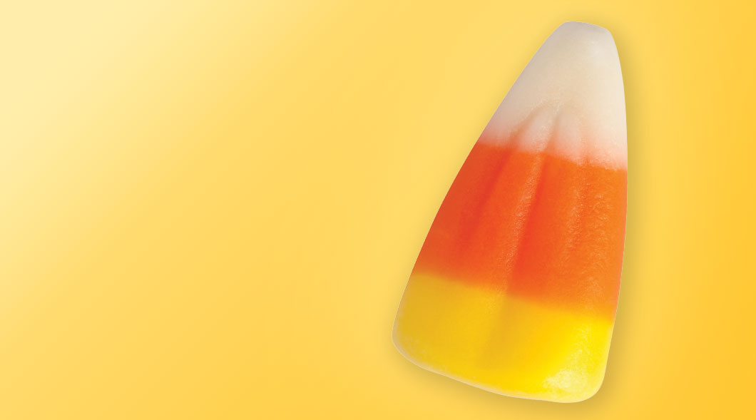 A piece of candy corn on a yellow background